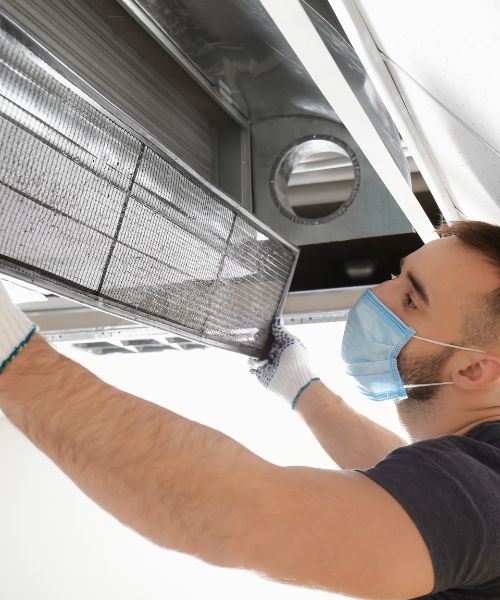 A Man Taking Down an Air Duct Filter