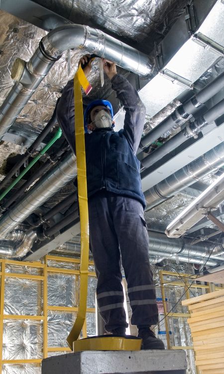 Hard worker wrapping an HVAC Air duct with foil tape Pensacola